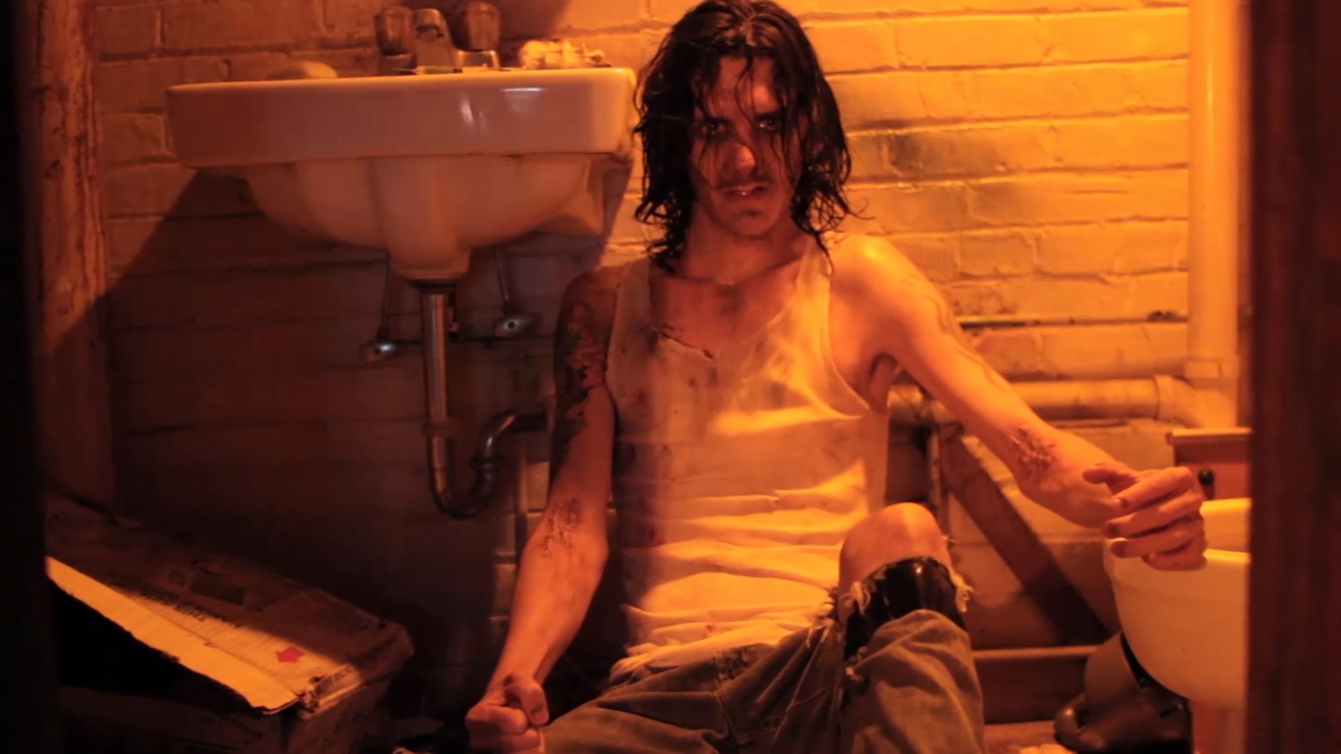 drug-addict zombie holding a knife sitting on a bathroom floor
